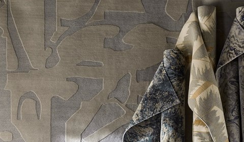 Various rolls of rugs stood up vertically against neutral tone rug backdrop